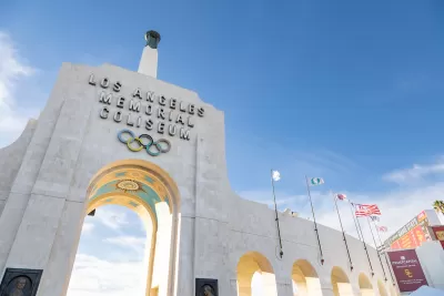 View looking up at stone entrance arch with name and Olympic rings at Los Angeles Memorial Coliseum.