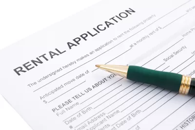 Close-up of rental application laying on table with green pen laying across the paper