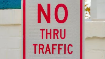 Close-up of white sign with red letters "NO THRU TRAFFIC"