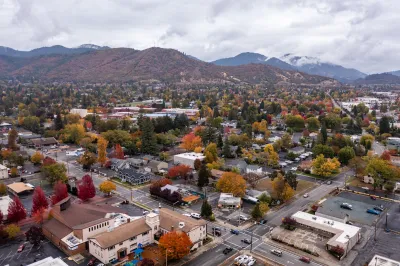 Aerial view of Grants Pass, Oregon with fall foliage and hills in background with a cloudy sky.