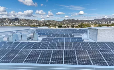 Large roof with solar panels and Los Angeles hills in background.