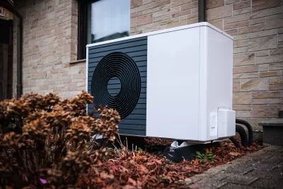 White geothermal heat pump installed on the side of a house