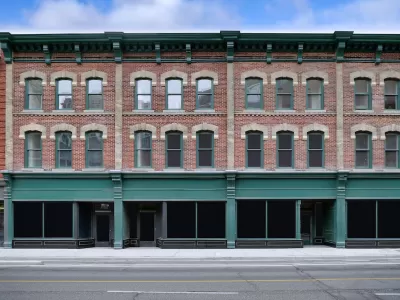Brick building with storefronts on ground floor and apartments on two floors above.