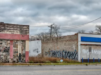 A vacant lot between two one-story brick buildings with graffiti in Detroit, Michigan