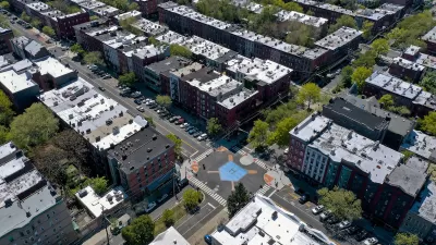 Aerial view of intersection in Hoboken, New Jersey with crosswalks, bulb-outs, and blue home plate painted in middle of intersection, surrounded by mid-rise multistory apartment buildings.
