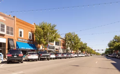 View of small-town street with brick buildings and cars parked in diagonal parking with string lights going across street in Cleveland County, Oklahoma.