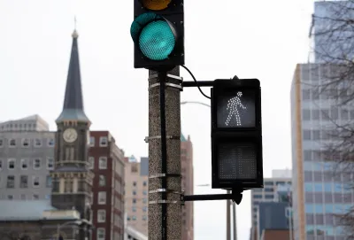 Close-up on pedestrian crosswalk light in downtown Milwaukee, Wisconsin with historic building with steeple visible in background.