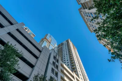 View from street level looking up at high-rise apartment building with multi0floor garage at bottom in Austin, Texas against blue sky