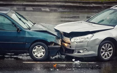 Two cars crashed head-on into each other on wet asphalt road.