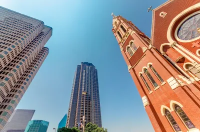 View up at brick Catholic church towers and modern high-rise buildings.