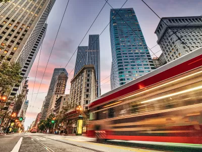 Blurred red San Francisco streetcar speeding past tall downtown buildings
