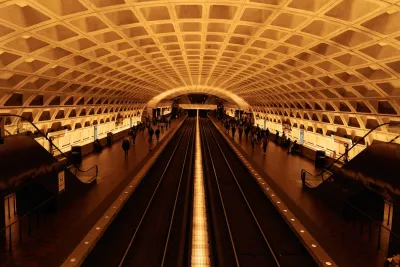 View of expansive subway station with curved roof and passengers waiting for trains in Washington, D.C.