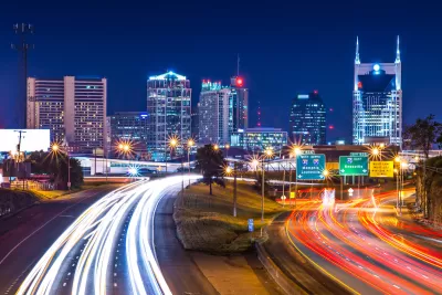 View of Nashville skyline at night with blurred highway lights in foreground.