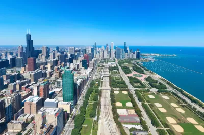 Aerial view of the Chicago Loop in summer from the south, with buildings on the left, Grant Park in the center, and Lake Michigan on the right.