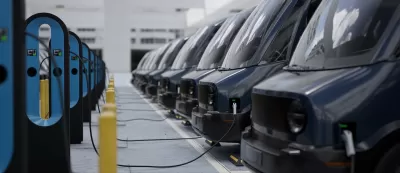 Close-up of fleet modern electric EV delivery vans being charged in covered parking garage.