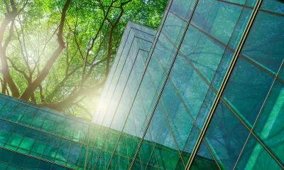 Glass building with green tree behind it.