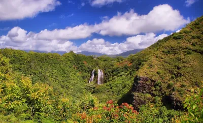 'Opaeka'a Falls on the island of Kauai surrounded by lush green forest and blue sky.