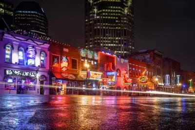 View from street level of brightly neon-lit bars and theaters on Broadway in downtown Nashville, Tennessee.
