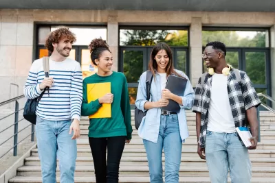 Happy students walking together on university campus, chatting and laughing outdoors after classes.