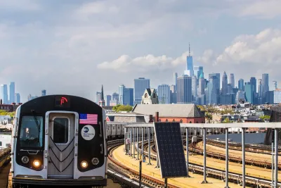 NYC MTA train on elevated rail with Manhattan skyline visible in background.