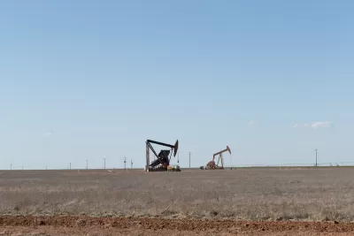 Two oil drilling derricks in vast field in West Texas.