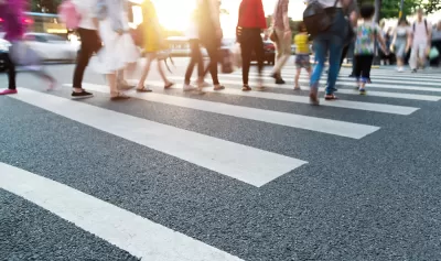 Close-up of blurred pedestrians crossing busy urban crosswalk.
