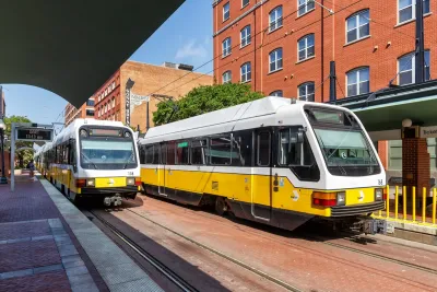 Two yellow and white Dallas Area Rapid Transit light rail streetcars at station in Dallas, Texas.