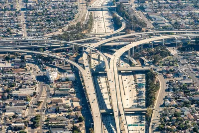 Aerial view of massive Los Angeles freeway interchange with dense housing and industrial areas around it.