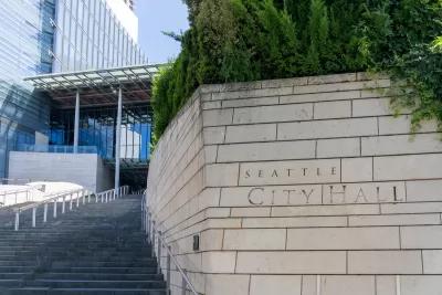 Close-up of engraved stone Seattle City Hall sign in front of wide steps leading to modern glass building.