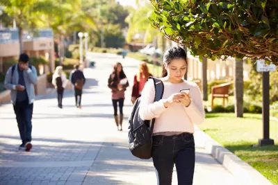 Students walking on sunny walkway on college campus.