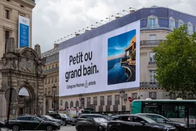 Large Airbnb billboard on neoclassical apartment building in Paris, France.