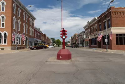 Red antique stoplight in the middle of wide intersection flanked by brick buildings in downtown rural Toledo, Iowa
