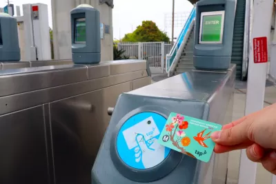 Hand holding up a TAP transit fare card to fare collection turnstile
