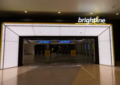 Empty, darkened corridor in transit station before opening with Brightline logo in lights on one side