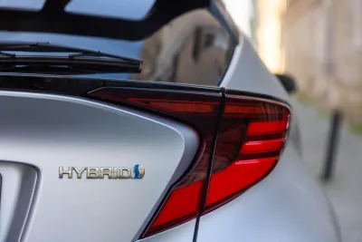 Close-up of Hybrid logo on back of silver Toyota sedan.