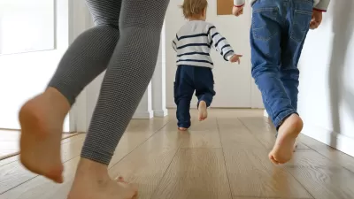 Close-up of two adults running after a small toddler in a bright apartment hallway