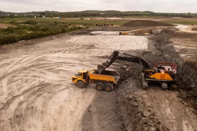 Aerial view of brownfield area with digger loading a dump truck.