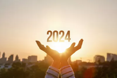 Graphic of person's hands with 2024 in middle against backdrop of city skyline and golden hour sky with rays coming through.