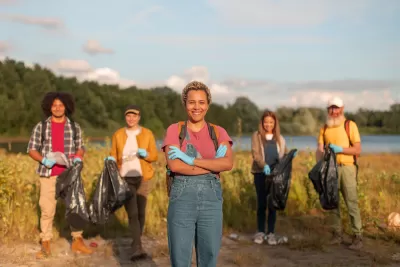 Group of five people standing in a wetland park smiling at the camera during a cleanup event.