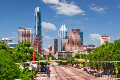 View of Congress Avenue with Texas state capitol dome among high-rise buildings in downtown Austin, Texas.