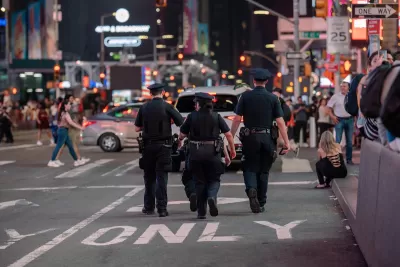 Three NYPD police officers walking away from camera in Times Square, Manhattan.