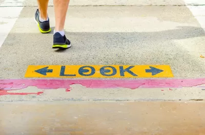 Close-up of "LOOK" sign on sidewalk with one pedestrian walking away.