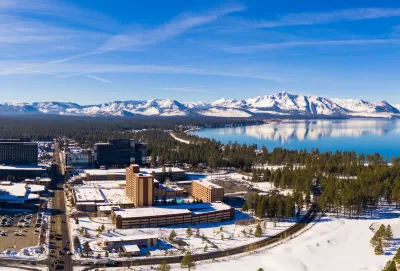Aerial view of snowy town of Stateline, Nevada on shore of Lake tahoe with mountains in background.