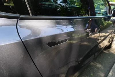 Close-up of door handle on outside of grey Tesla electric car.