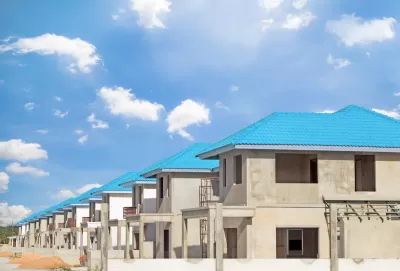 Row of concrete two-story homes with blue tile roofs under construction.