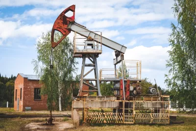 Old oil well with red brick building in the background.