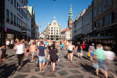 Blurred pedestrians on busy walkable street in Copenhagen, Denmark with old buildings in background