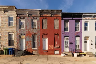 Row of colorful boarded-up brick two-story townhomes in baltimore, Maryland.
