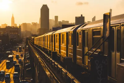New York City subway train on elevated track in yellow light.