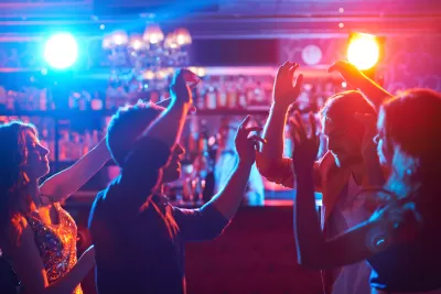 Dark shot of people dancing in front of bar with red and blue atmospheric lights